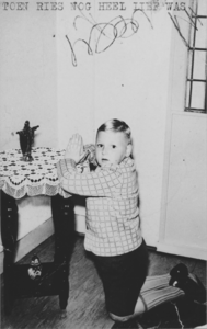 876462 Portret van Ries de Winter uit Wijk C, geknield voor een tafeltje met een Christusbeeldje. Ries is de zoon van ...